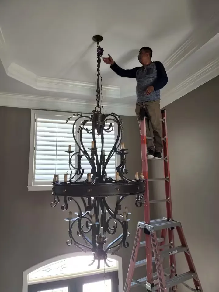 Large foyer chandelier installation in Atlanta with technician working from a ladder