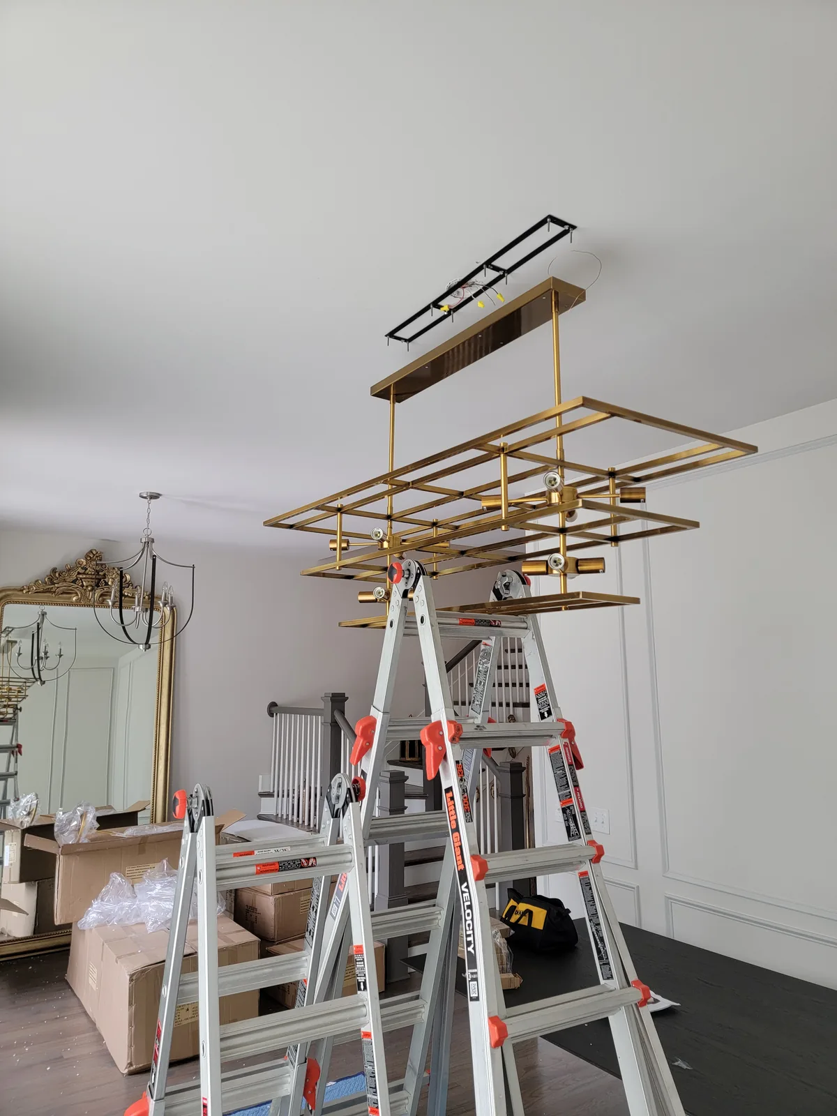 Modern rectangular chandelier installation in Atlanta with ladder setup