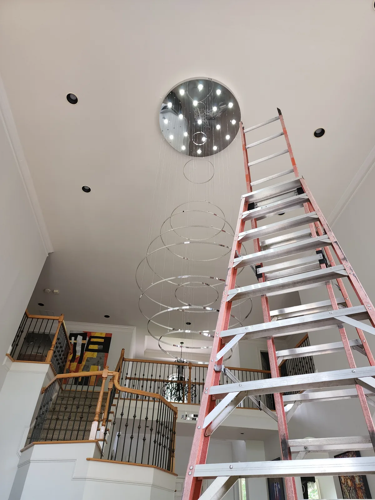 Modern suspended globe chandelier being assembled and installed from a ladder in Atlanta